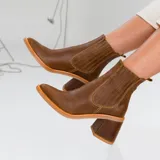 Botas cortas de cuero color marrón, con taco de madera forrado en cuero, elástico lateral y punta fina.