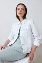 Campera de jean blanca con cuello clásico, bolsillos con solapa abotonados en el pecho y cierre frontal con botones metálicos. Corte recto.