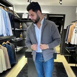 Campera tejida gris con cierre frontal, cuello alto y bolsillos laterales.