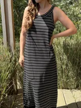 Vestido largo de punto, negro con rayas horizontales blancas, corte recto y sin mangas.