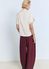 Camisa color crema de manga corta con tejido satinado, corte regular, cuello camisero y cierre delantero con botones.