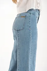 Jean de mezclilla azul claro, tiro medio, corte recto con leve campana al tobillo. Presenta costuras verticales marcadas en el frente y en los laterales de las piernas, y terminación deshilachada en el ruedo.