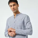 Camisa celeste de lino con cuello mao, manga larga con puños abotonados, cierre frontal con botones y bolsillo de parche en el pecho.