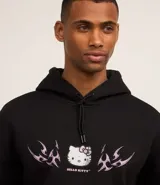 Buzo negro con capucha y cordón de ajuste, con estampa frontal de Hello Kitty y detalles tribales en color rosa. Tiene bolsillo tipo canguro y puños ajustados.