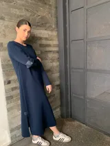 Vestido largo de lana color azul marino, con cuello redondo, mangas largas y parches de cuero en los codos. Presenta aberturas laterales en el ruedo.