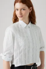 Camisa cropped blanca de manga larga con detalles de volados y pliegues verticales en el frente.