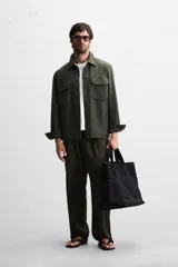 Sobrecamisa color beige de corte relaxed fit, con cuello solapa, manga larga con puños abotonados, bolsillos de plastrón con solapa en el pecho y bolsillos de vivo en la cadera. Cierre frontal con botones.