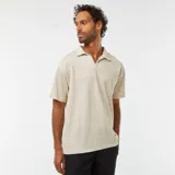 Remera tipo polo color beige claro, de manga corta y corte holgado.