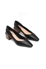 Zapato de cuero negro con punta elegante, ligeramente espigada, y taco cuadrado de madera.