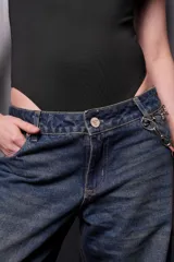 Pantalón de jean azul oscuro de corte ancho con cadena decorativa en la cintura.