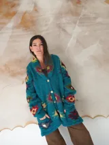 Saco de lana marrón con diseño geométrico multicolor, cuello con solapa, cierre frontal con botones y bolsillos delanteros.