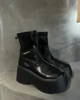 Botas negras de caña media con plataforma gruesa y cierre frontal con cremallera.