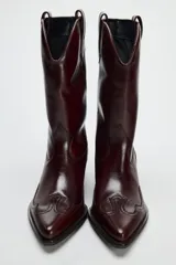 Bota de cuero color bordó, estilo cowboy, con puntera marcada y tiradores laterales.