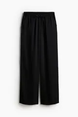 Pantalón negro de corte holgado en sarga suave, tiro alto, cintura elástica con cordón ajustable, bolsillos laterales y piernas amplias.