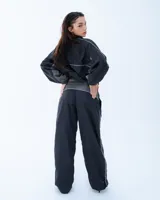 Pantalón deportivo negro con recortes en gris y vivos blancos. Tiro medio, corte holgado, cintura elastizada y cierre en los tobillos.