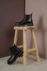 Bota Chelsea de cuero negro con elástico lateral y suela track.