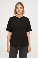 Remera negra de poliéster, manga corta, corte holgado y cuello redondo.