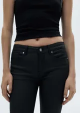 Pantalón de jean negro skinny con acabado encerado, tiro bajo, cinco bolsillos y cierre de cremallera y botón.