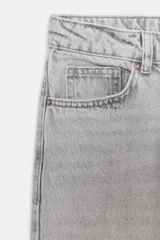 Jeans de tiro alto color negro lavado, con cintura cruzada, cinco bolsillos y pernera recta. El bajo está acabado en vuelta y tiene cierre frontal cruzado con cremallera y botones.