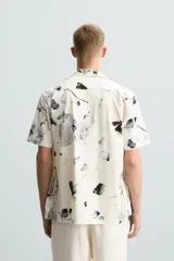 Camisa de manga corta con cuello bowling y estampado floral en tonos blanco y negro.