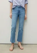 Pantalón de jean celeste de corte cropped y estilo flare, con tiro medio, cinco bolsillos, trabillas y bajo deshilachado.
