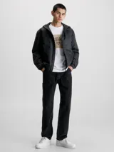 Campera cortavientos negra con capucha, confeccionada en poliéster reciclado. Cuenta con cierre de cremallera, puños y bajo elásticos, bolsillos laterales y logo de Calvin Klein en la manga.