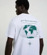 Remera blanca de algodón con corte clásico, cuello redondo y mangas cortas. Presenta estampado frontal con una brújula, un mapa y la inscripción "Sun Route Sailboat".