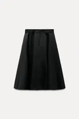 Falda midi negra de gabardina, tiro medio, cintura con trabillas, corte evasé con volumen y cierre frontal con cremallera y botón.