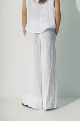 Pantalón blanco de lino, de corte palazzo y cintura con cordón ajustable.