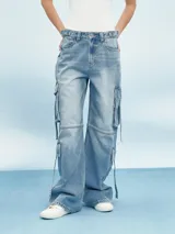 Pantalón de jean celeste con corte ancho, bolsillos laterales tipo cargo y cordones ajustables en la parte inferior.