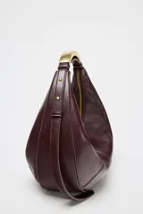 Bolso de mano ovalado color marrón oscuro, con asa de hombro metálica dorada y cierre superior con cremallera.