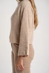 Sweater de punto acanalado color marrón, con cuello alto tipo polera y mangas largas de corte ancho. Posee un diseño oversize confeccionado en mezcla de lana.