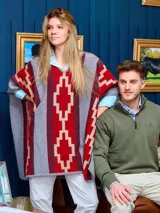 Poncho con escote en V, color gris con guardas rojas y beige. Confeccionado en Uruguay con lana lambswool.