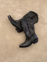 Botas de cuero negro con bordado decorativo en el caño y empeine, taco bajo y punta fina. Diseño de estilo cowboy.