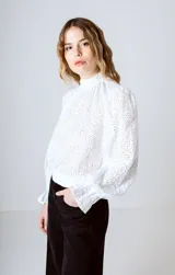 Blusa blanca de broderie con cuello alto, mangas largas abullonadas y puños elásticos.