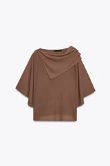 Top color crema de tejido de punto, con cuello asimétrico y mangas anchas.