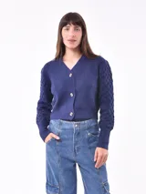 Saco tejido color azul con diseño de rombos en mangas y cuerpo, con cuello en V y cierre frontal con botones dorados.