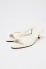 Sandalia tipo mule de charol color blanco, con tira delantera y tacón fino medio.