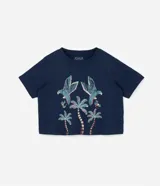 Remera cropped de algodón azul marino, con cuello redondo, mangas cortas y estampa delantera de guacamayas y cocoteros.
