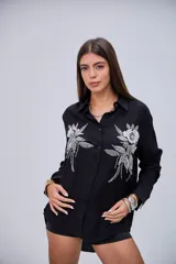 Camisa negra de manga larga con cuello clásico y botones frontales. Presenta dos grandes apliques bordados con lentejuelas y cuentas en forma de flores y hojas en la parte delantera.