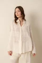 Camisa de manga larga color crema, confeccionada en algodón con bordados florales. Presenta cuello clásico, cierre frontal con botones y corte holgado.