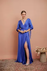 Vestido largo de satén color azul eléctrico, con escote en V cruzado, mangas 3/4 con lazos en los puños y tajo lateral alto.