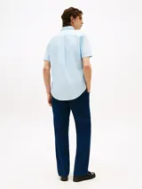 Camisa celeste de corte regular, confeccionada en algodón Oxford con cuello abotonado, manga corta y logo de Tommy Hilfiger bordado en el pecho.