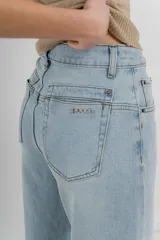 Pantalón de jean celeste claro, corte palazzo, tiro alto, bolsillos delanteros y traseros, y detalle metálico con el logo Peach en el bolsillo trasero.