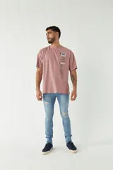Remera color rosa viejo de corte amplio con estampa en el frente que incluye texto y diseño gráfico.