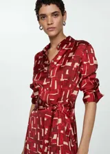 Vestido camisero midi con estampado abstracto en tonos rojo y beige, cuello camisero, manga larga y lazo ajustable en la cintura.