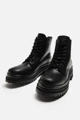 Bota de cuero negra con cordones, caña media y suela track.