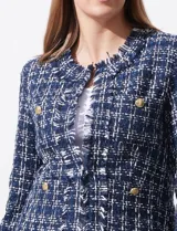Chaqueta tipo blazer en tejido tweed azul con detalles en blanco y lurex. Tiene escote mao, abertura central, bolsillos delanteros y puños con aplique de botones perlados. Terminación desflecada y forro interno.