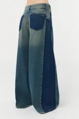 Jean wide leg de denim 100% algodón con recortes laterales de un lavado más oscuro y bolsillos traseros y relojero con ese mismo lavado. Tiene un lavado localizado sobre tono color efecto vintage en frente y espalda.