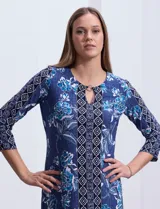 Vestido corto azul con estampado floral y geométrico, cuello redondo con abertura y aplique metálico, y mangas 3/4.